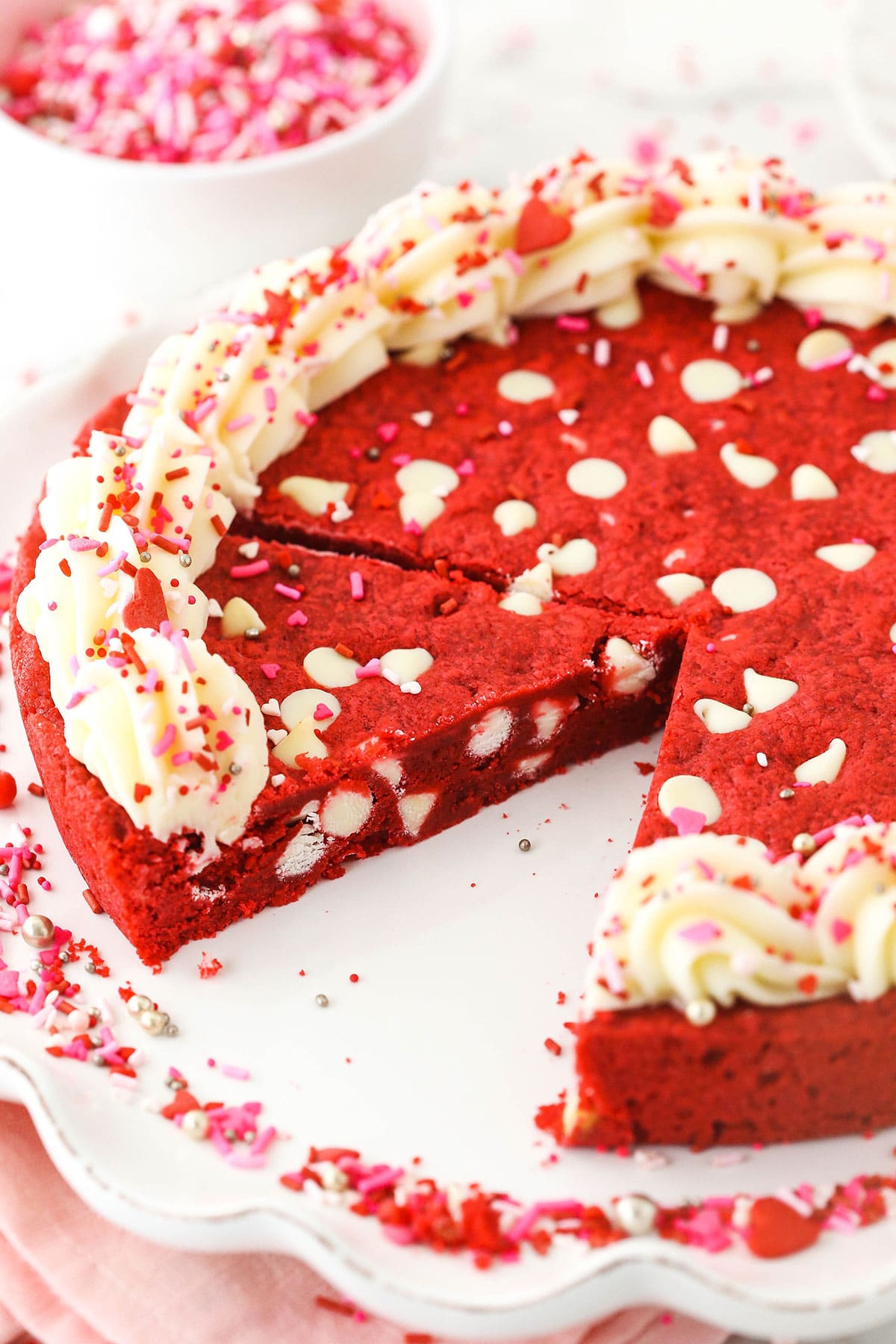 A cookie cake on a serving dish with one slice removed from the plate and a second slice cut off of the cake