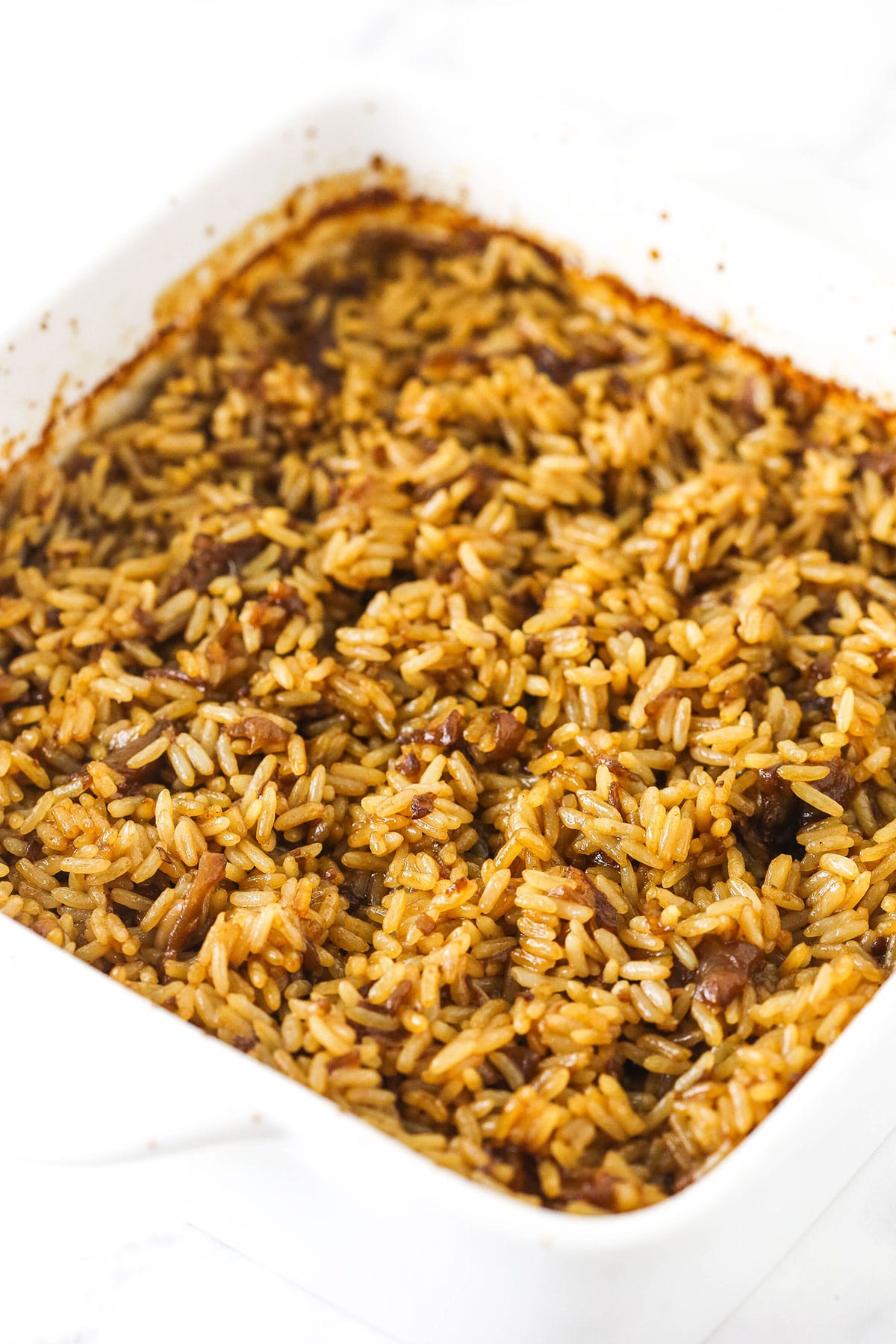 A batch of baked butter rice inside of a square baking dish