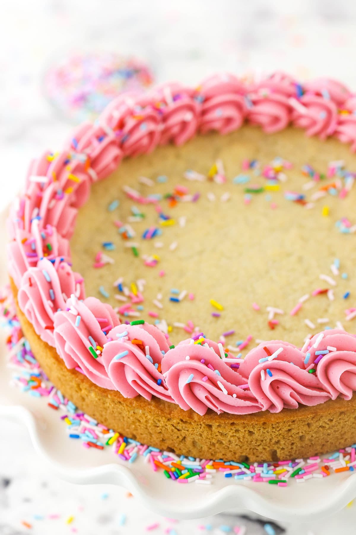 Overhead shot of a sugar cookie cake with frosting and sprinkles.