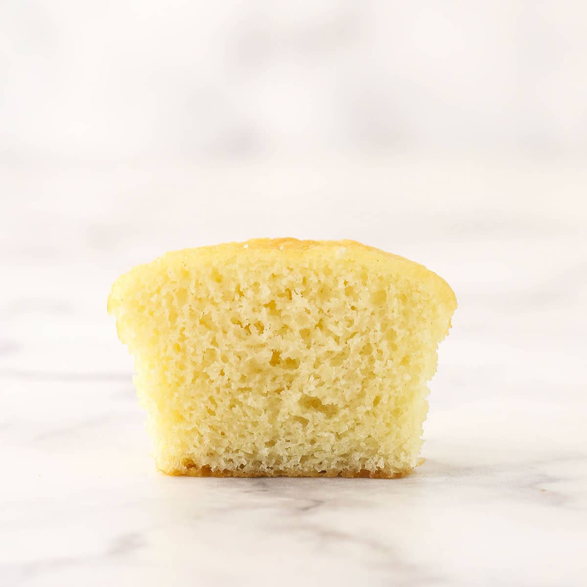 A moist vanilla cupcake cut in half to reveal its interior