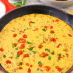 Rotel dip in a cast-iron skillet. Salsa and chips are nearby on the table.