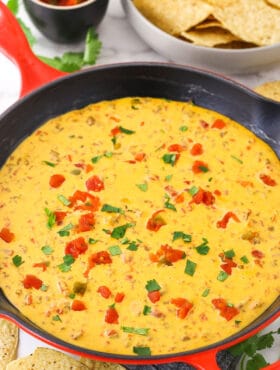 Rotel dip in a cast-iron skillet. Salsa and chips are nearby on the table.