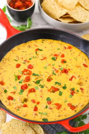 Rotel dip in a cast-iron skillet. Salsa and chips are nearby on the table.