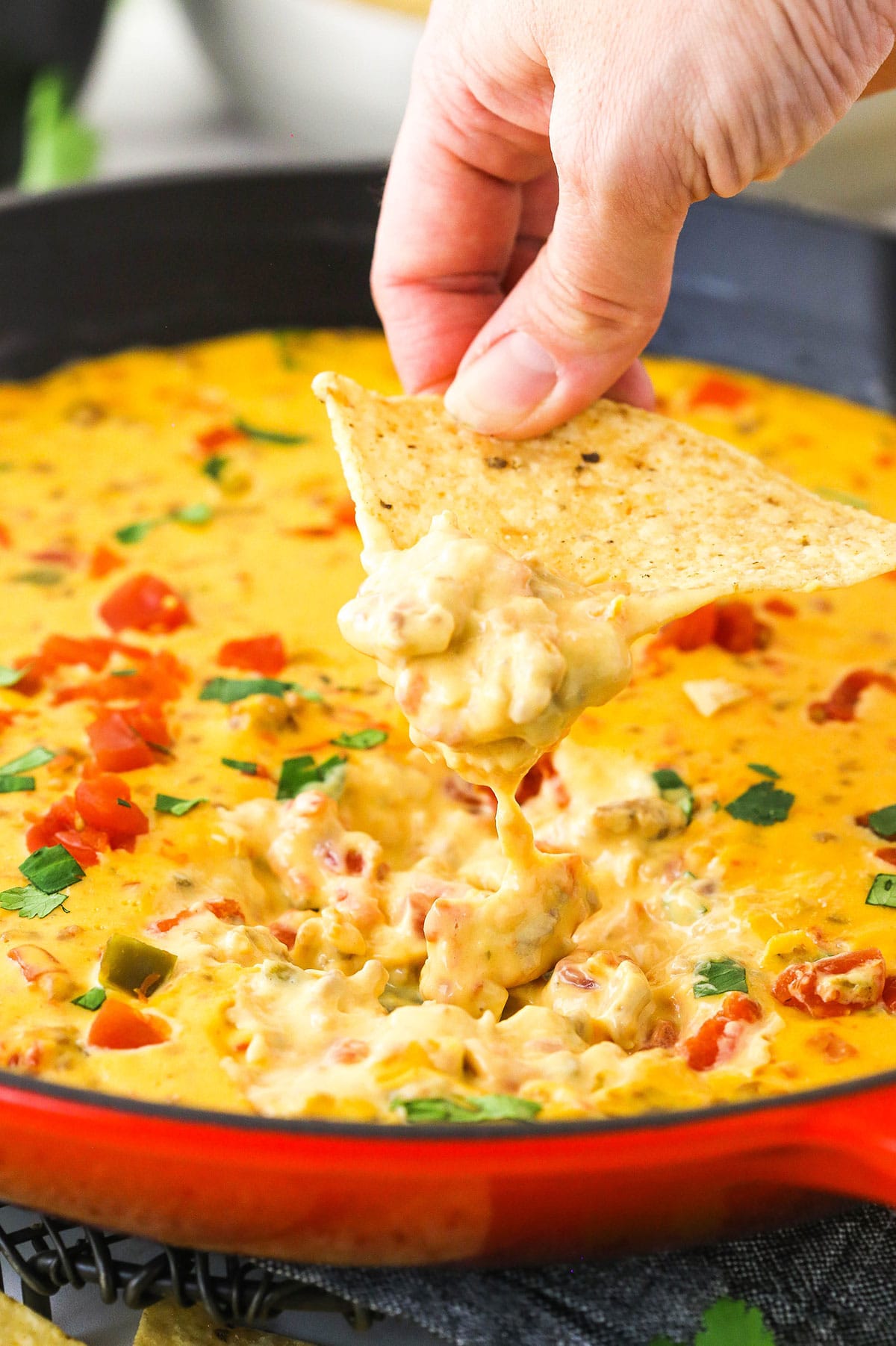 Cheese dip being lifted out of a skillet on a tortilla chip.