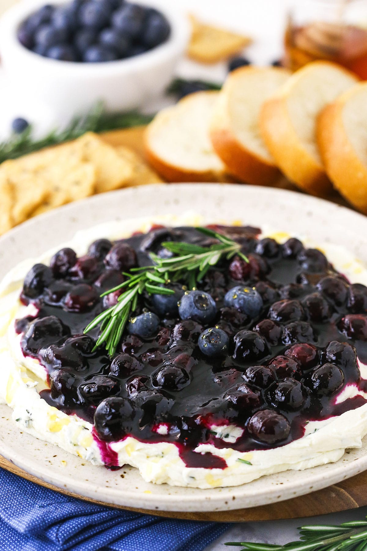 The dip on a large serving platter with a bowl of fresh blueberries behind it