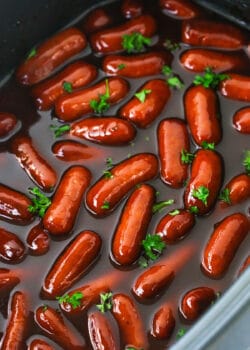 A Crockpot filled with cocktail weenies and a mixture of BBQ sauce and grape jelly