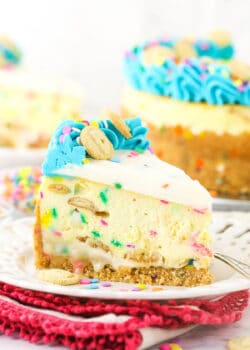 A piece of Dunkaroos cheesecake on a dessert plate with the remaining cake in the background