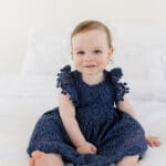 McKenzie sitting on a bed and looking at the camera with a sweet smile