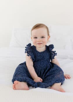 McKenzie sitting on a bed and looking at the camera with a sweet smile