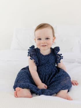 McKenzie sitting on a bed and looking at the camera with a sweet smile