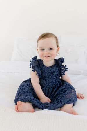 McKenzie sitting on a bed and looking at the camera with a sweet smile