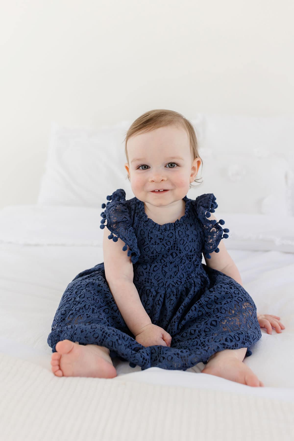 McKenzie sitting on a bed and looking at the camera with a  sweet smile