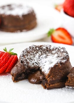 chocolate lava cake with lava center on white plate and sliced strawberry