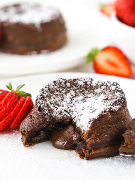 Chocolate lava cake with lava center on white plate and sliced strawberry