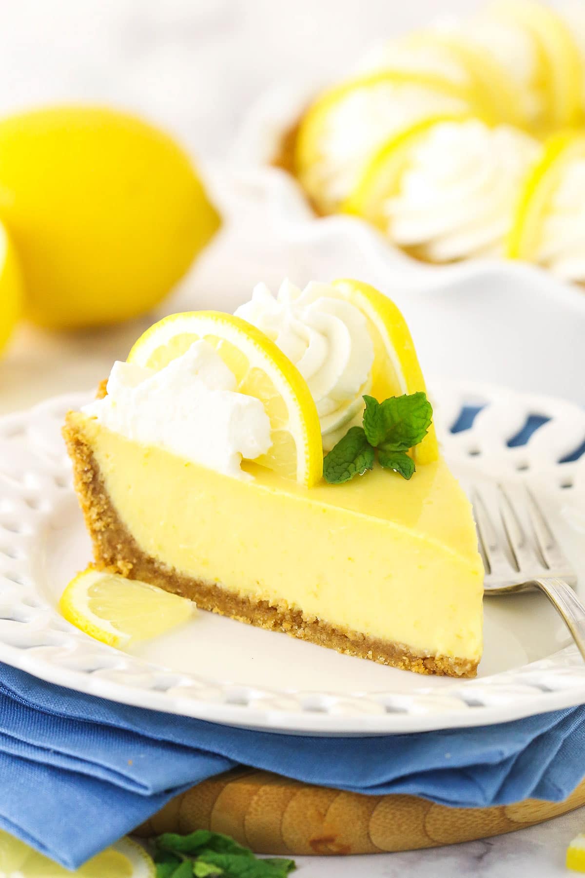A piece of lemon pie on a dessert plate with a metal fork beside it