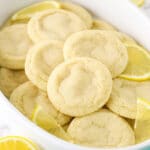 A Tupperware tub filled with lemon sugar cookies and a few fresh lemon slices