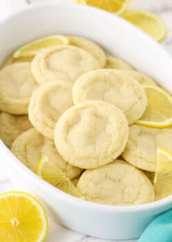 A Tupperware tub filled with lemon sugar cookies and a few fresh lemon slices