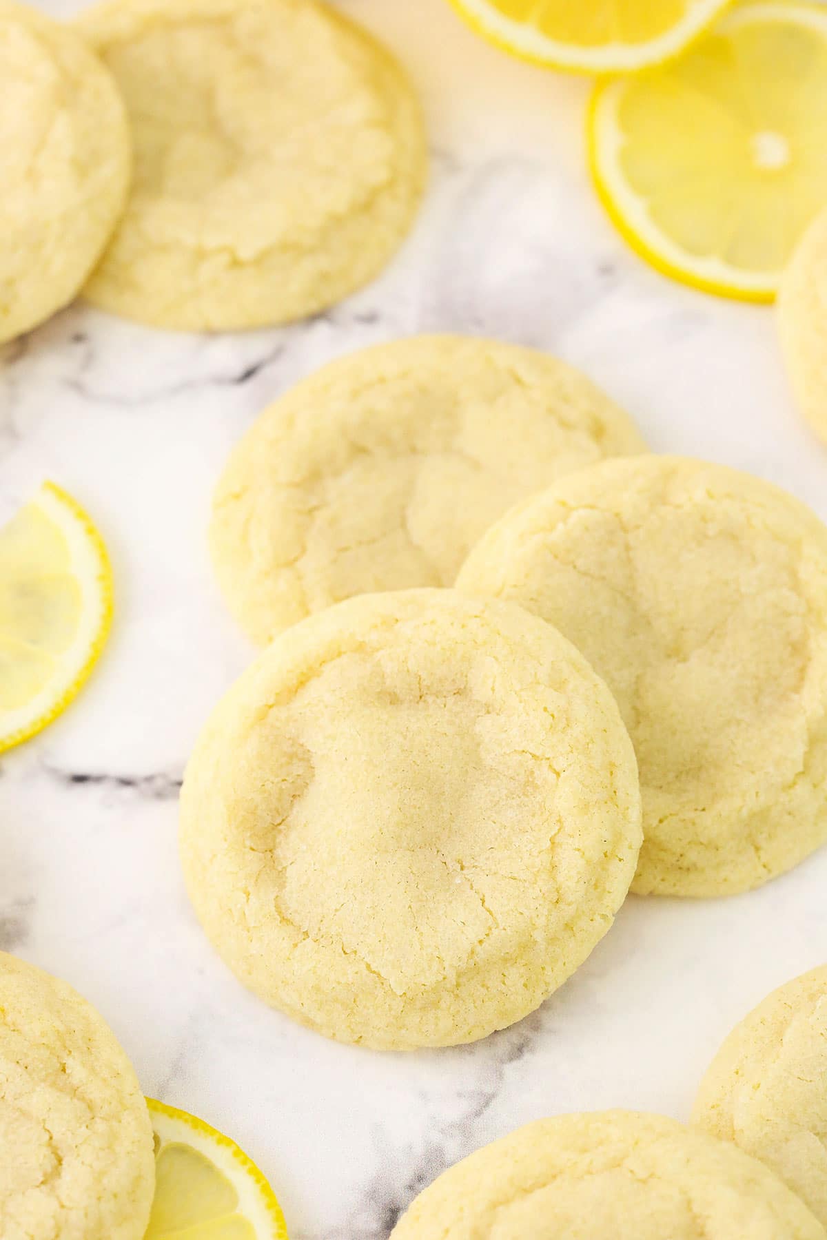 Three citrus cookies on a countertop with six more cookies partially in view