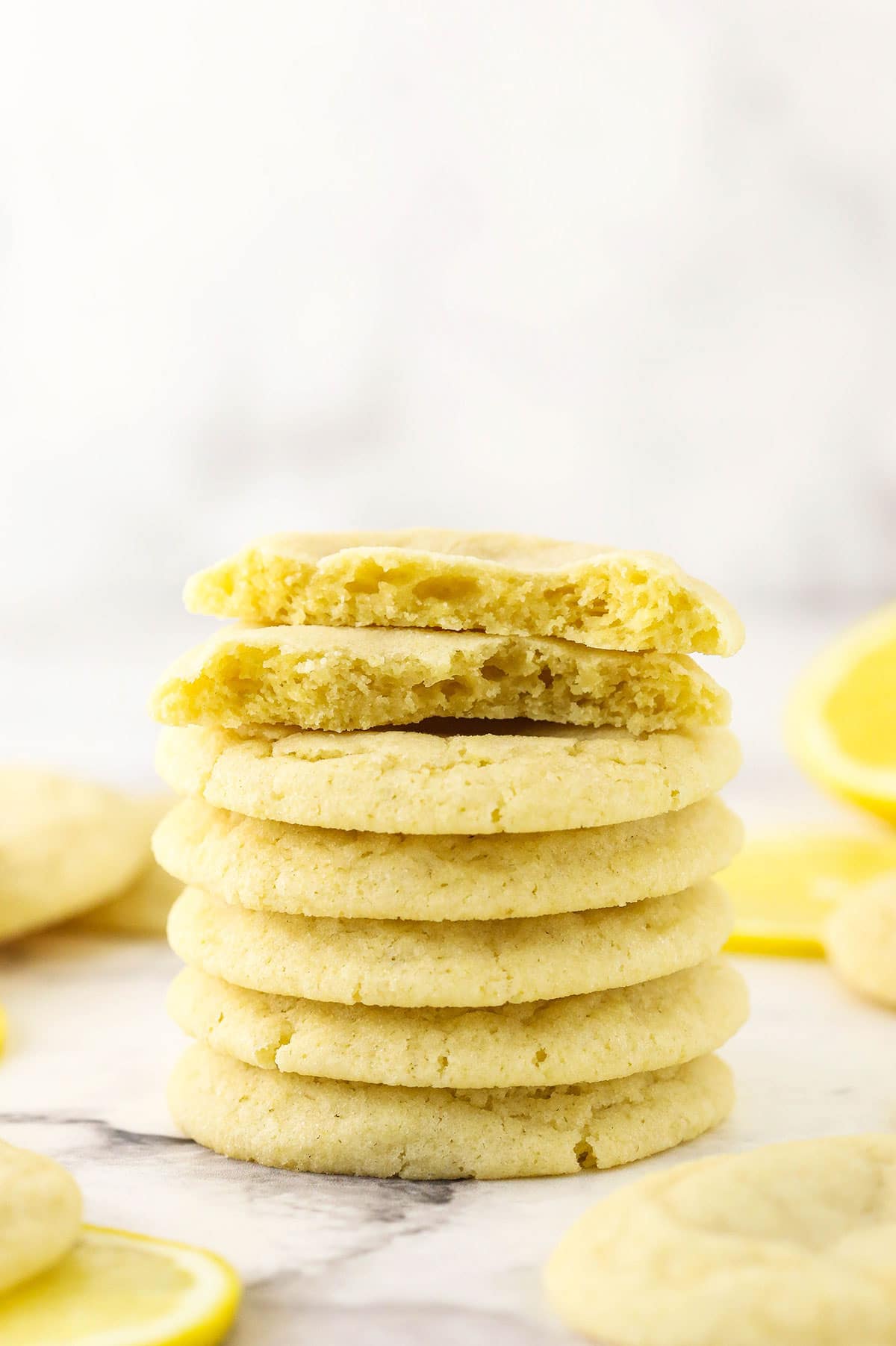 A stack of seven lemon sugar cookies with the top two cookies cut in half to reveal their fluffy interiors