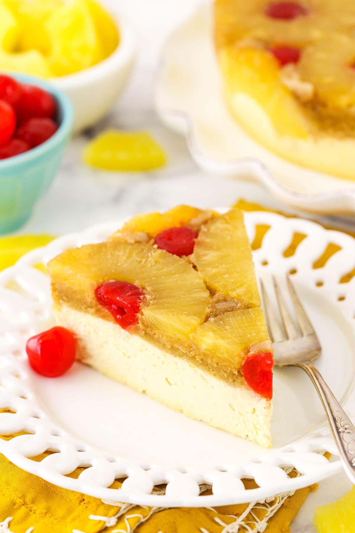 A slice of pineapple cheesecake on a small white plate with a fork.