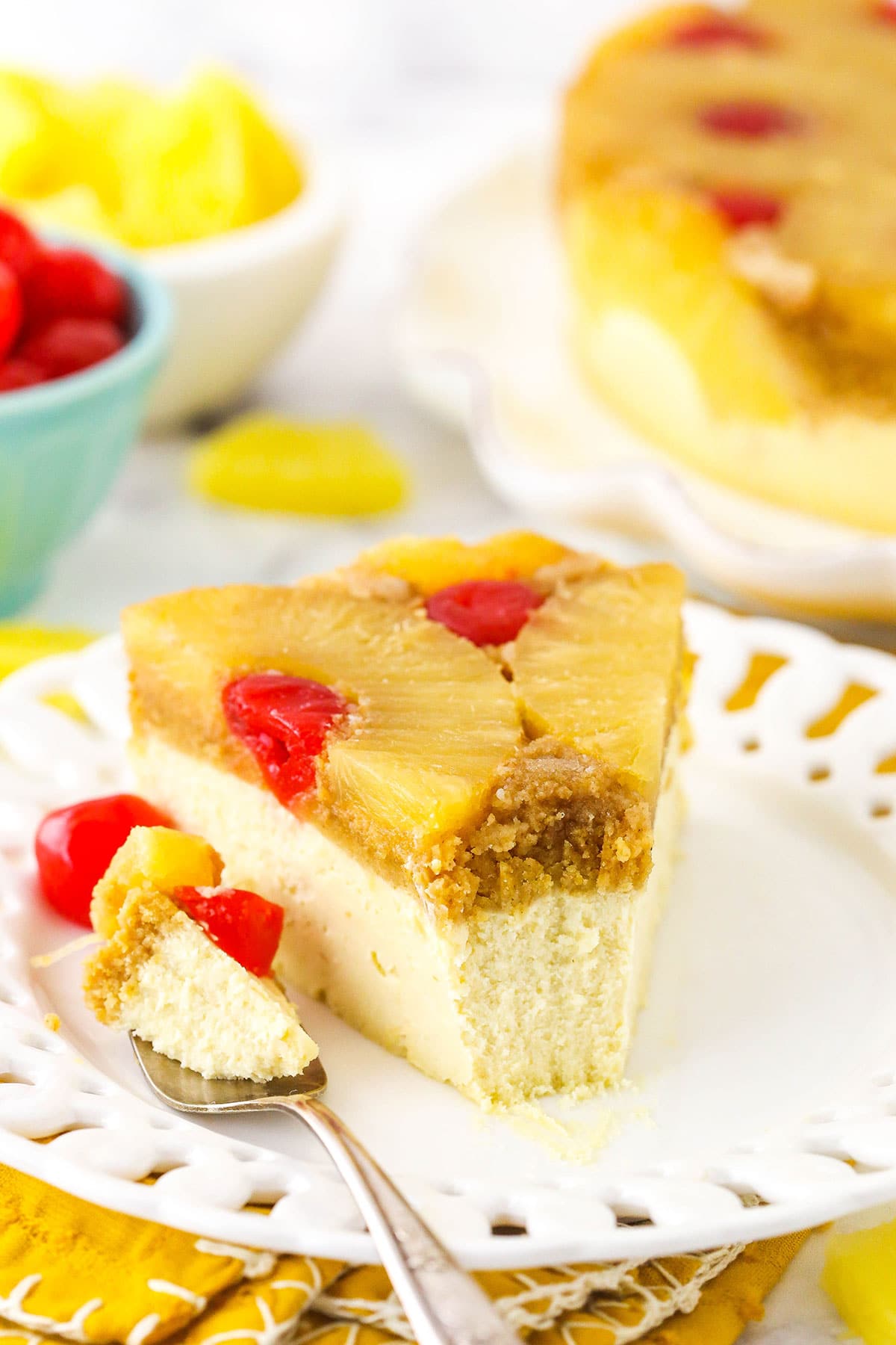 Cheesecake topped with fruit. One bite of the cheesecake is lying on a fork on the dessert plate.