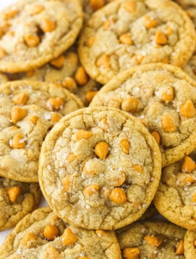 Close up of salted butterscotch cookies piled on a white countertop.