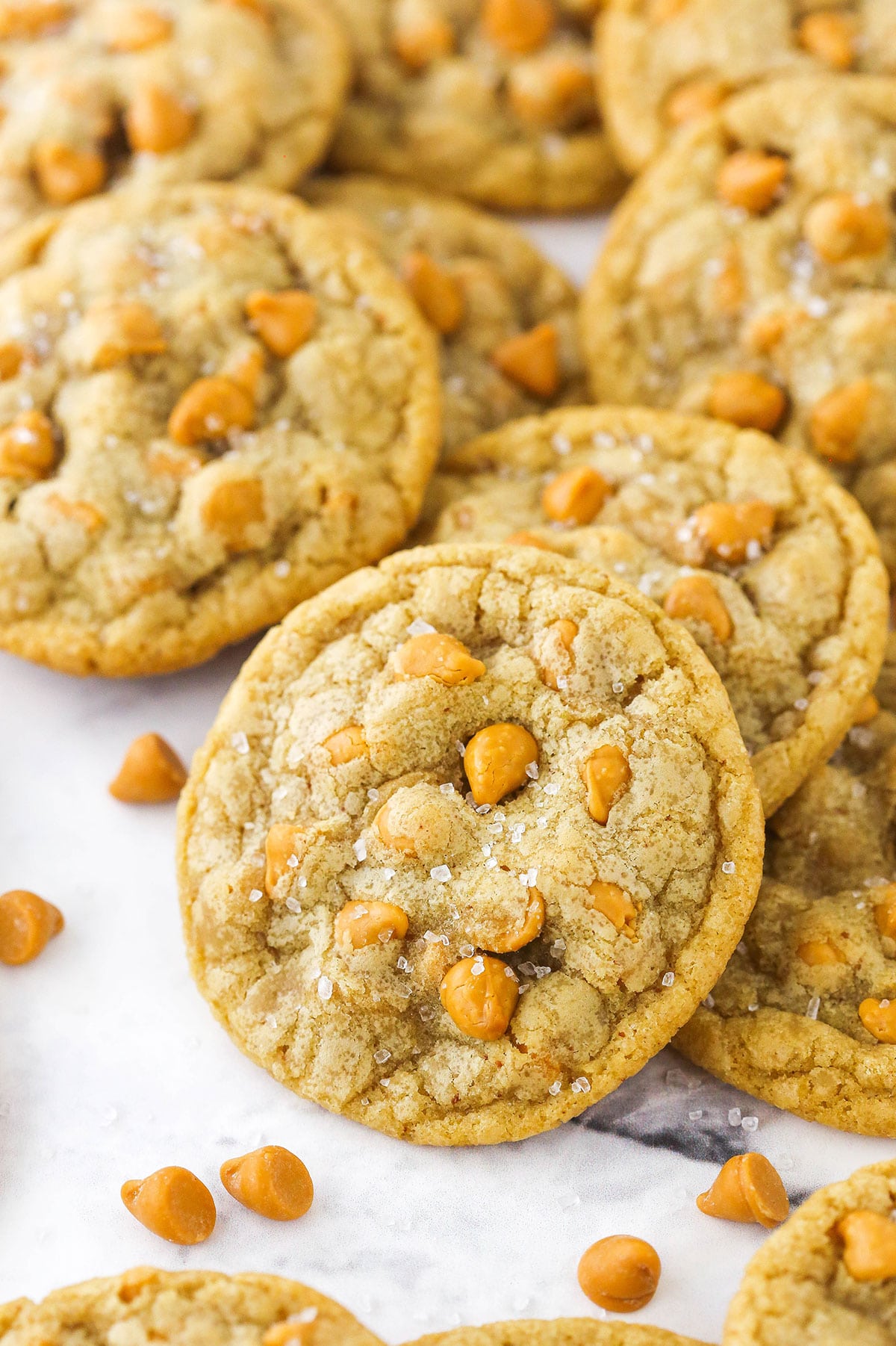 Salted butterscotch cookies piled on a white countertop.
