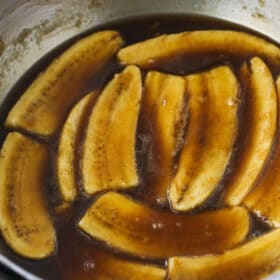 A close-up shot of cooked bananas inside of a bowl with homemade cinnamon sauce