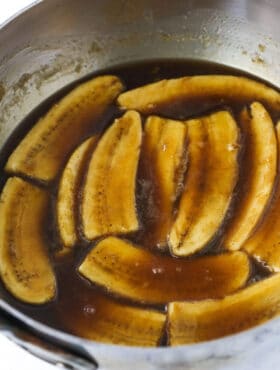 A close-up shot of cooked bananas inside of a bowl with homemade cinnamon sauce