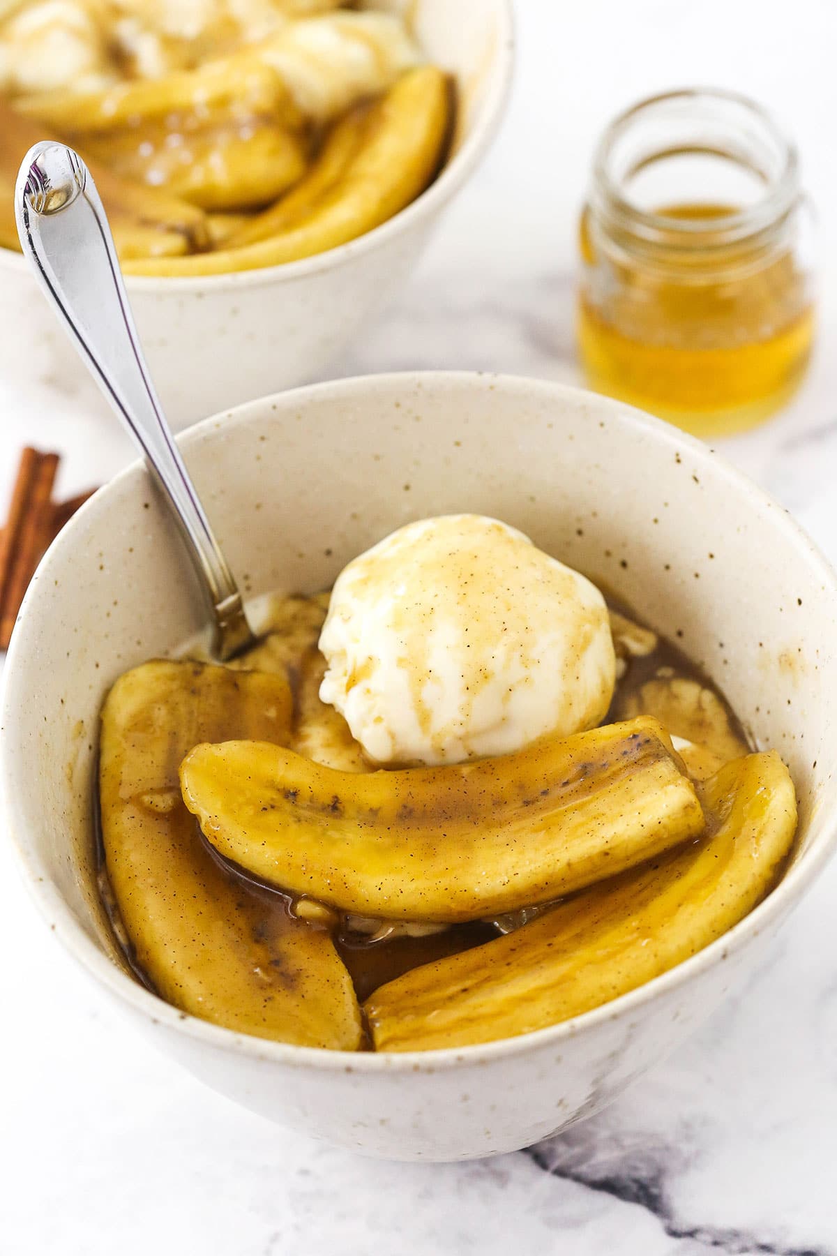 Bananas foster inside of a bowl with a small scoop of vanilla bean ice cream on top