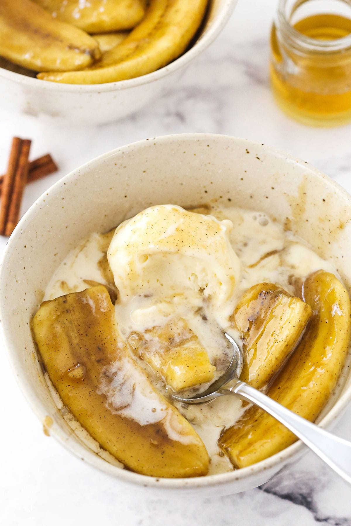Bananas foster in a speckled bowl over a melty scoop of ice cream