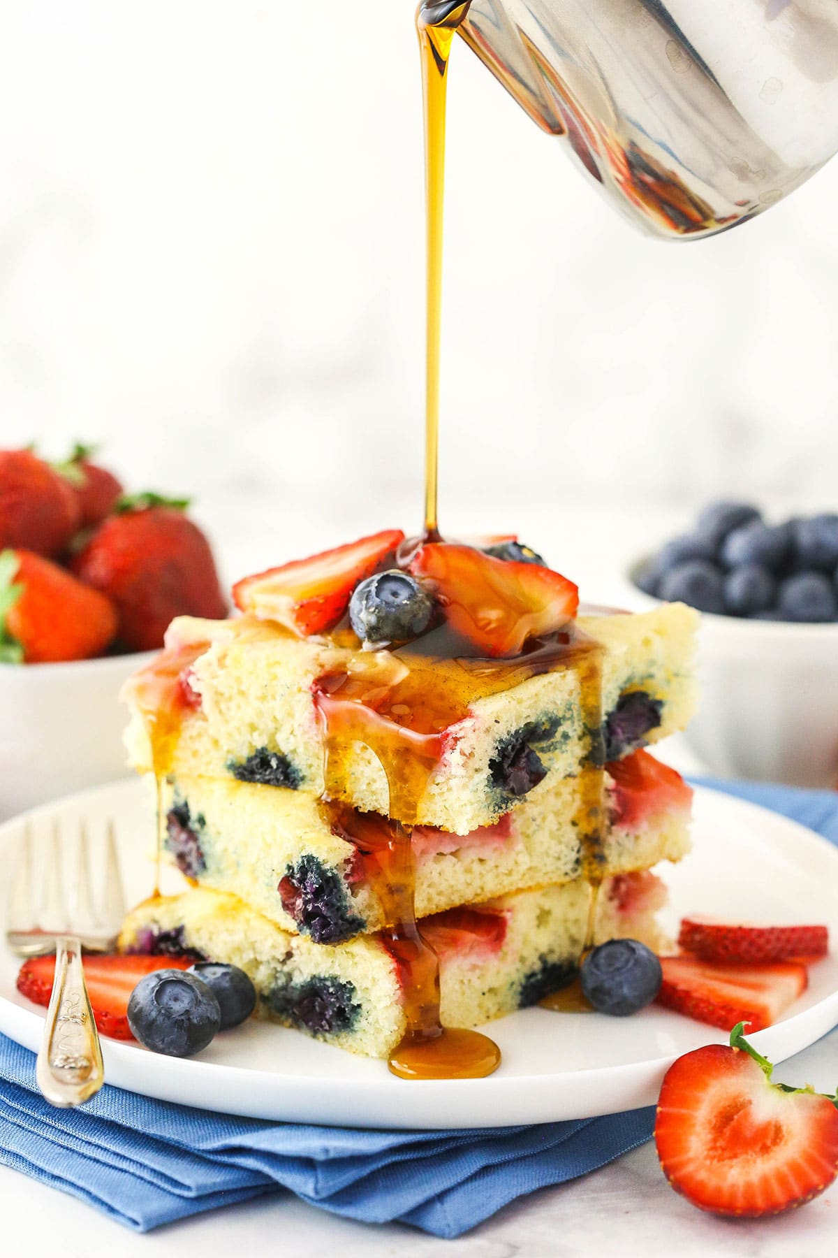 Three oven-baked flapjacks with pure maple syrup being poured over them