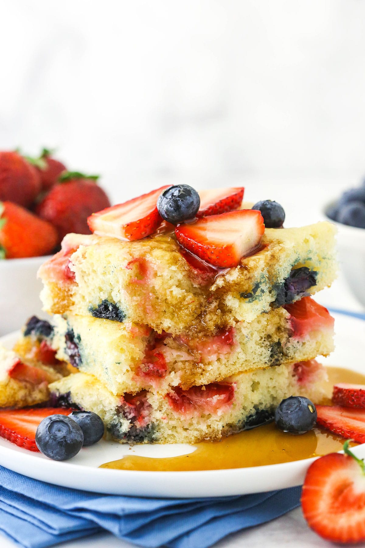 A stack of fluffy homemade oven pancakes with maple syrup soaking into them