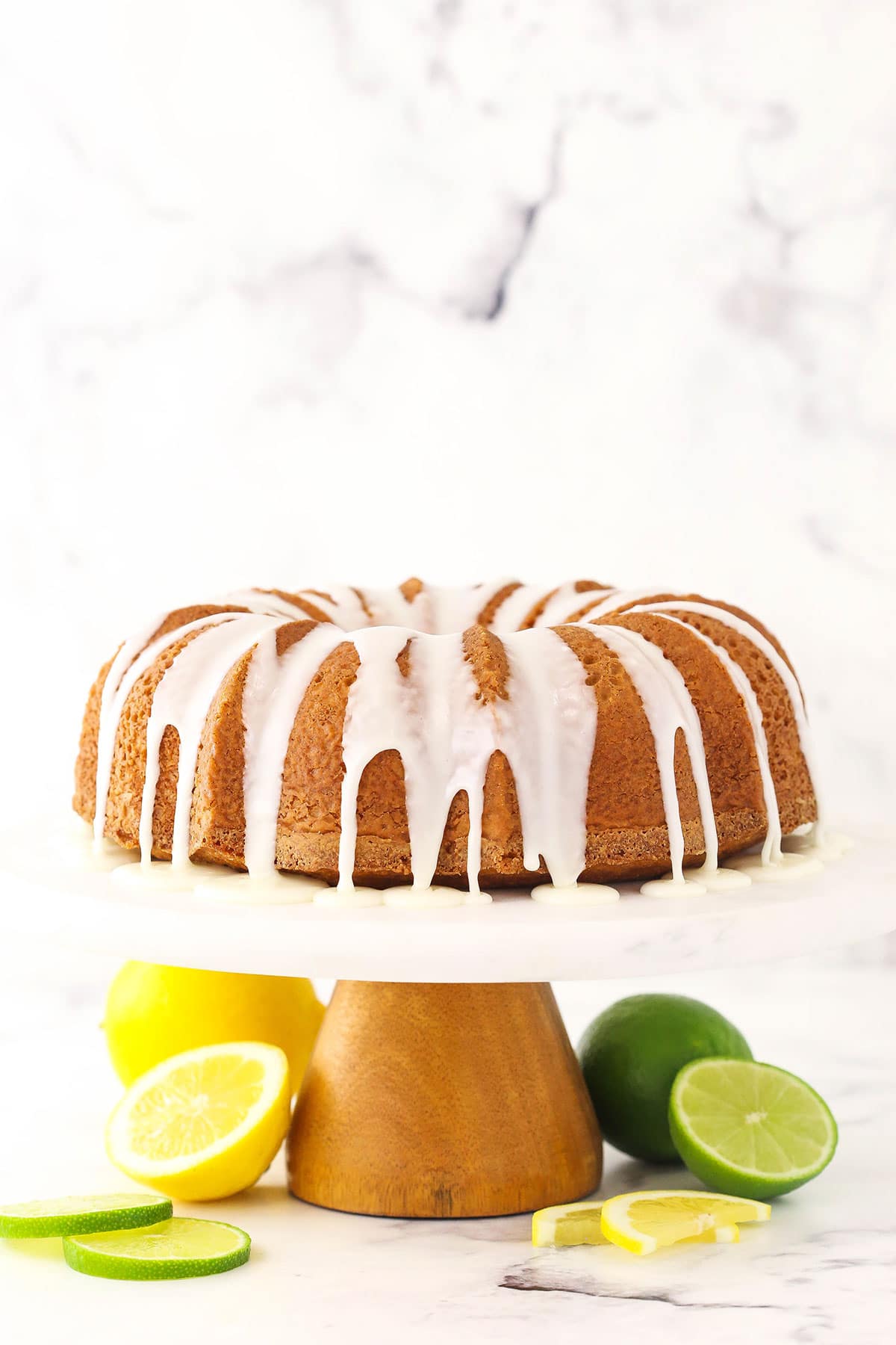 A 7UP pound cake on a cake stand that has a wooden base and a plastic platform