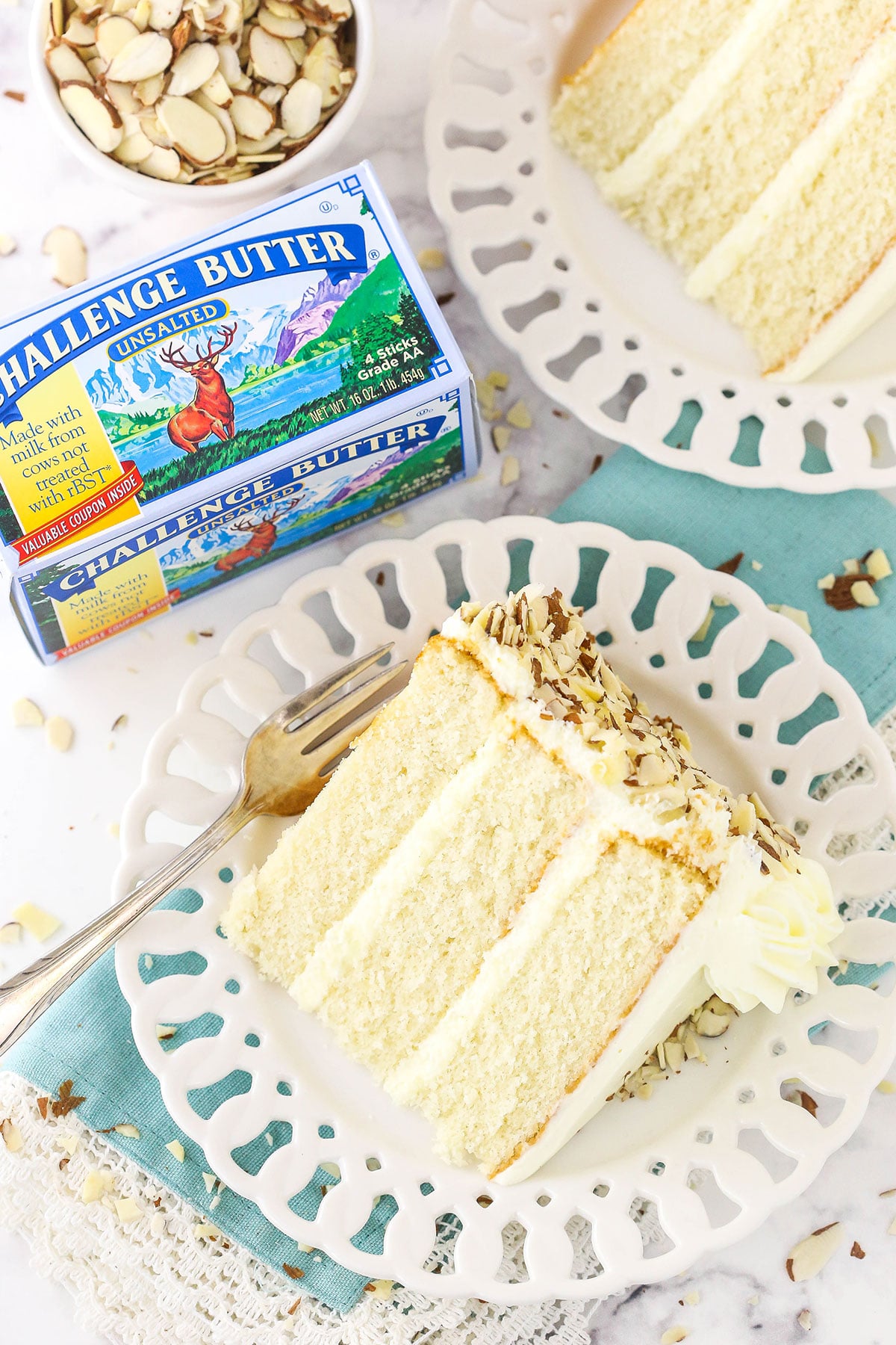 two slices of cake on white plates with challenge butter next to them