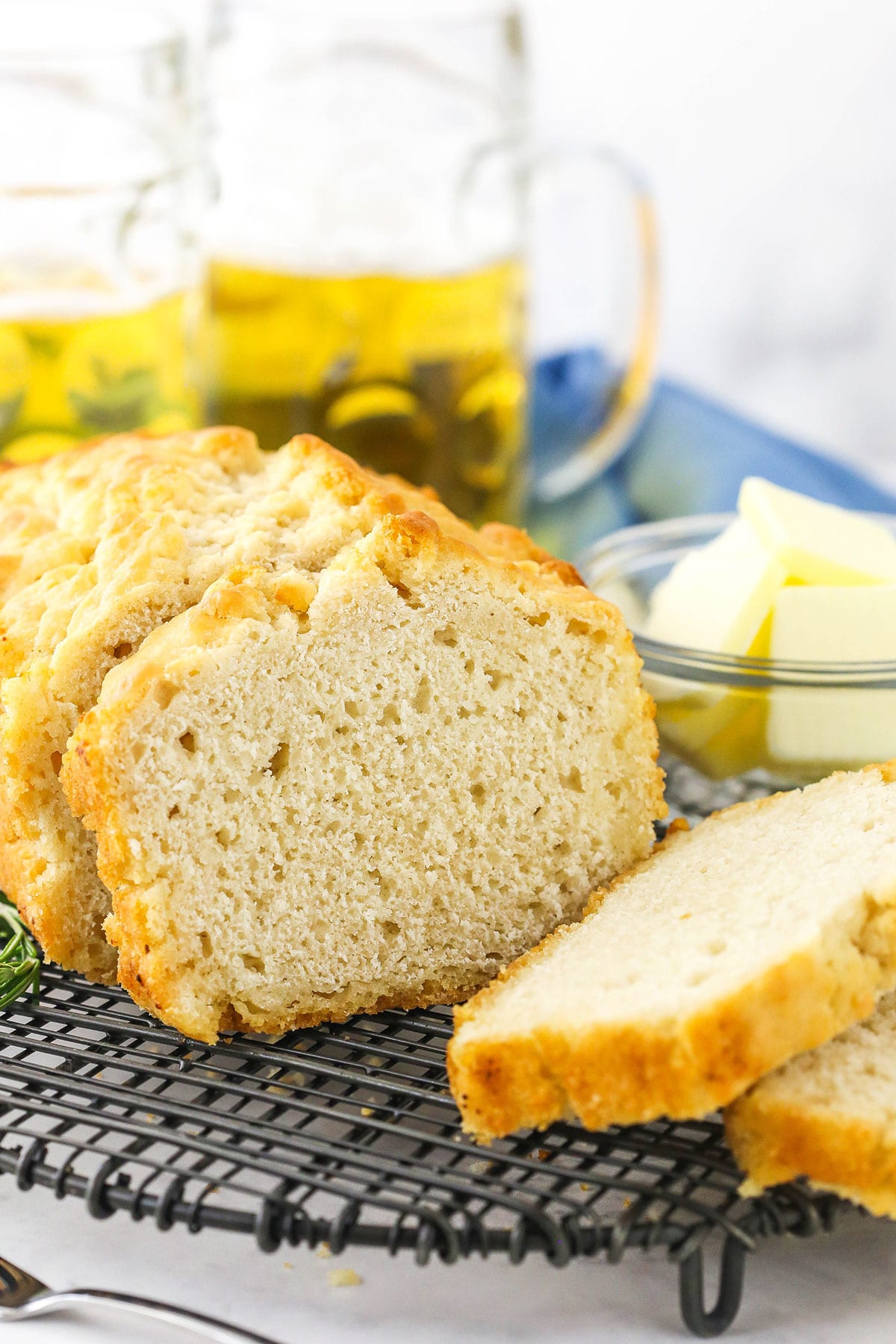 A loaf of homemade quick bread on a wire rack with three slices cut off the loaf