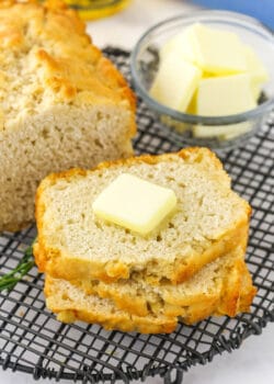 A slice of beer bread on a cooling rack with a pat of butter on top
