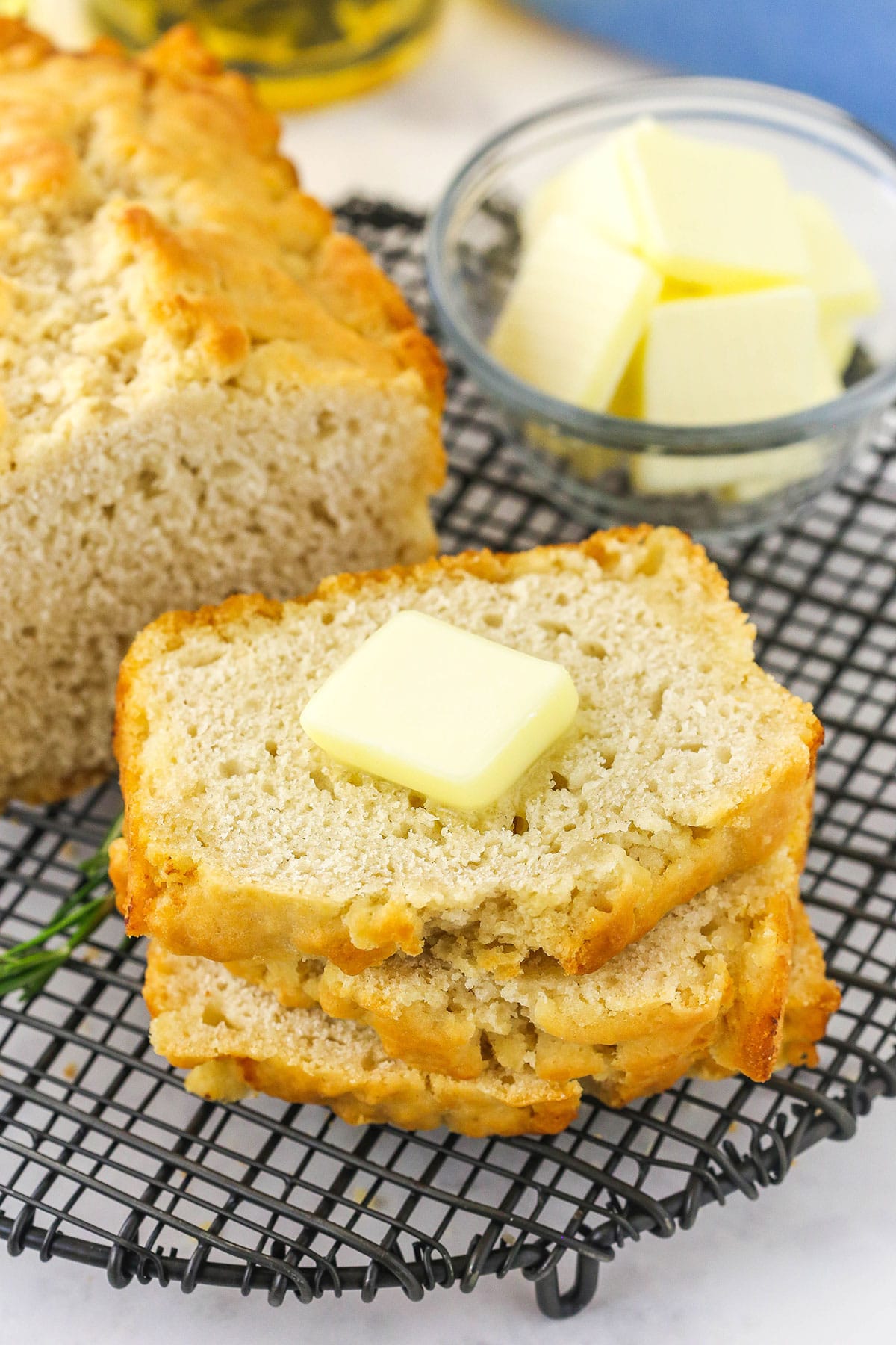 A slice of beer bread on a cooling rack with a pat of butter on top