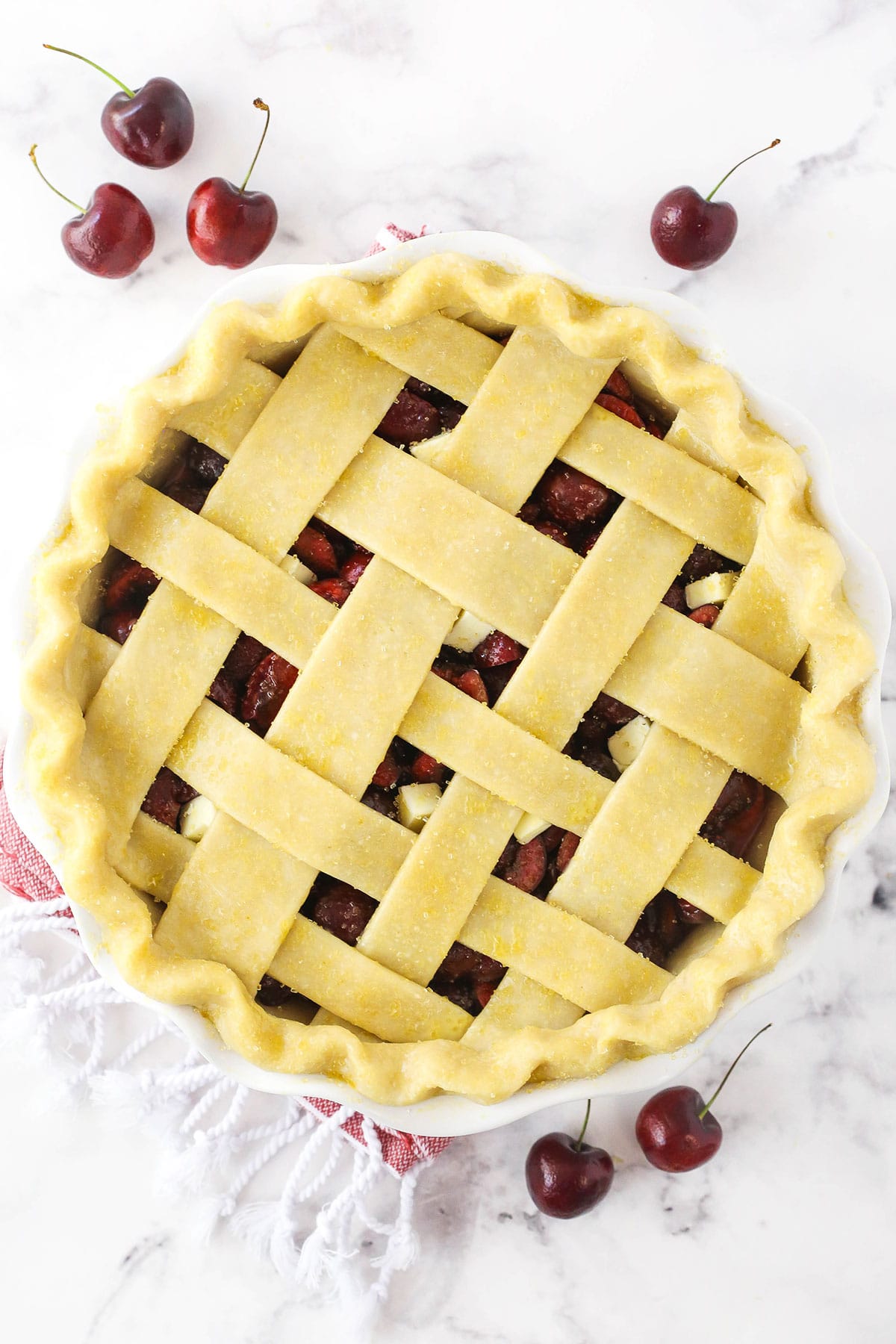 An unbaked pie with a lattice crust on top after it has been brushed with eggwash and sprinkled with turbinado sugar