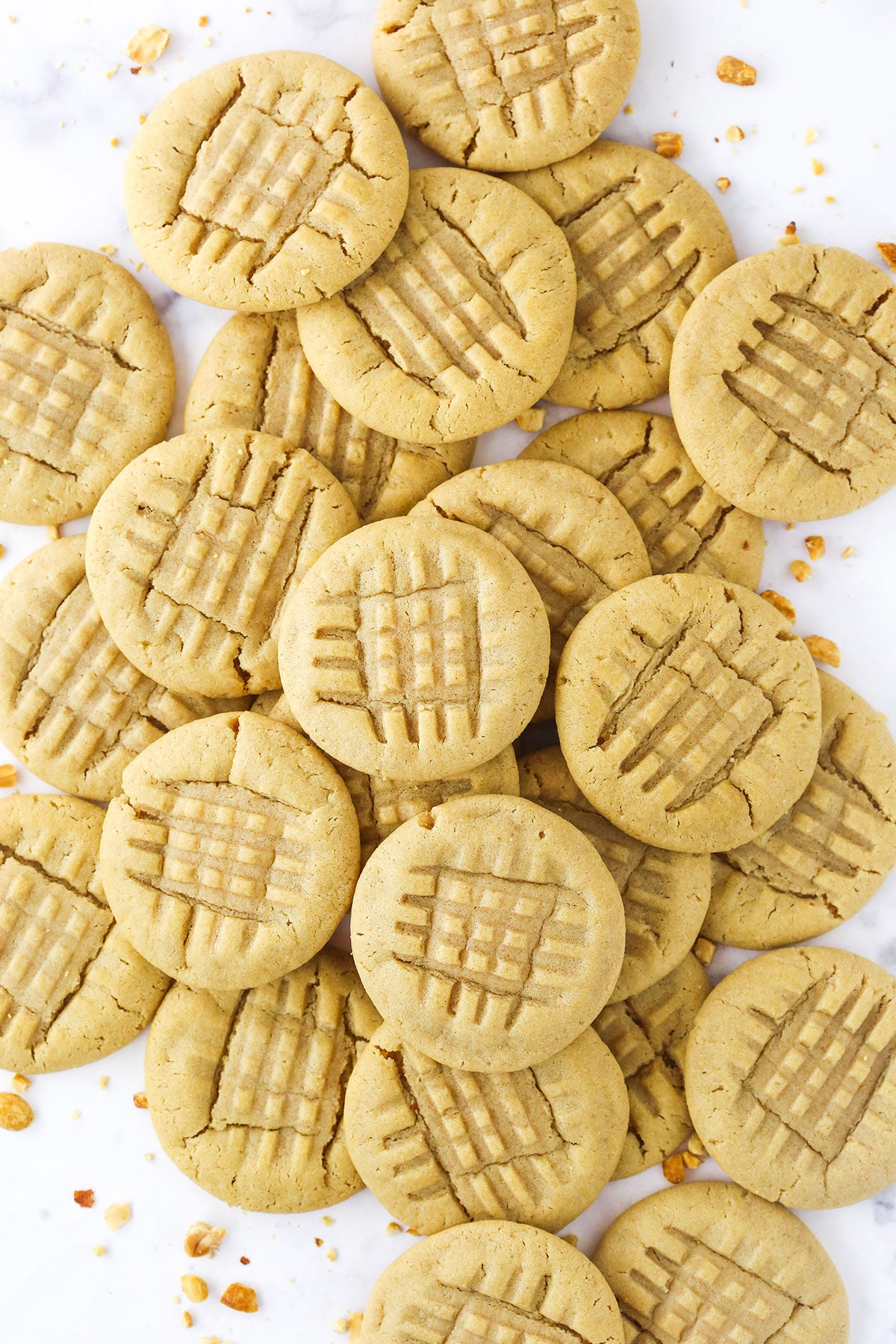 Classic peanut butter cookies piled onto a kitchen countertop