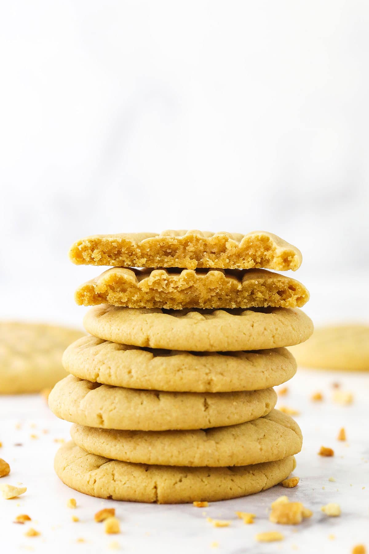 Six homemade peanut butter cookies stacked on top of each other with the top one broken in half