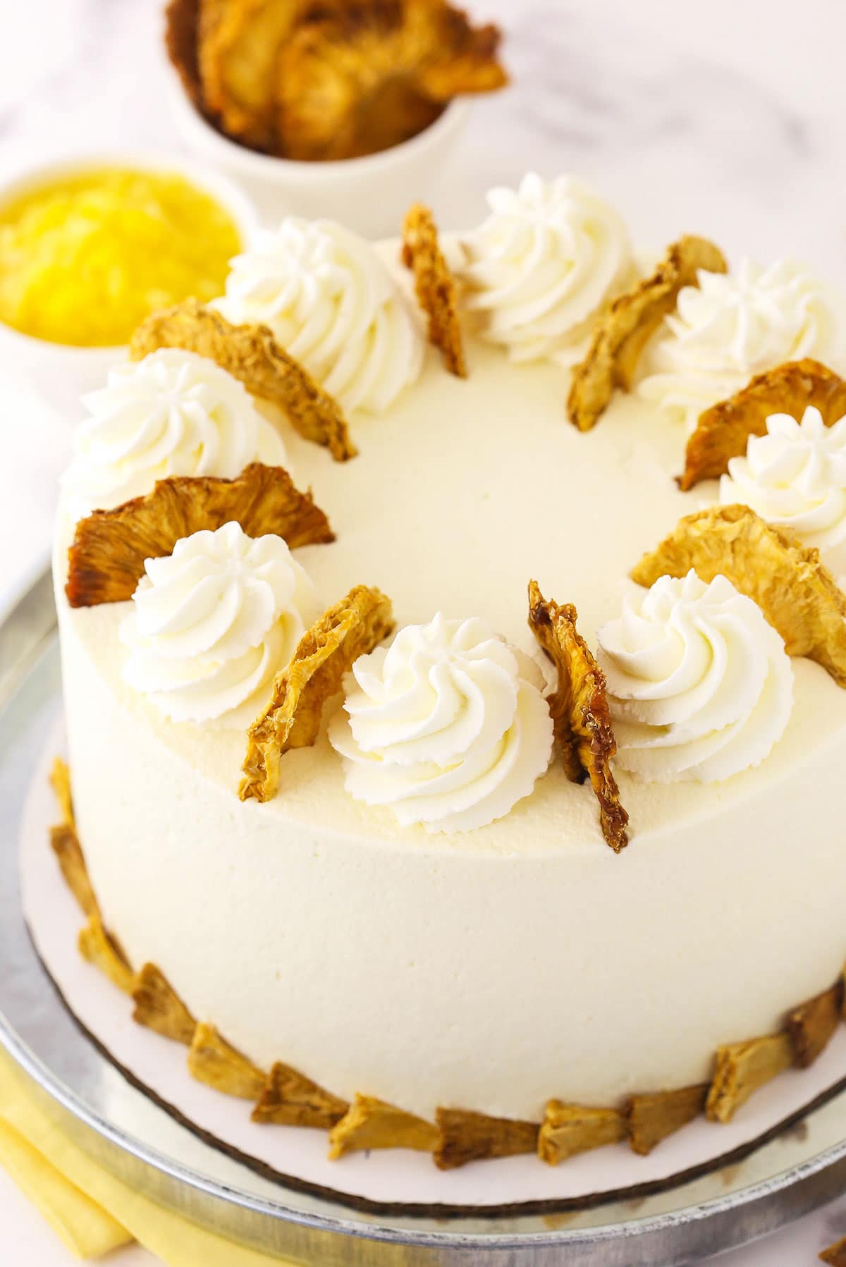 A frosted and decorated pineapple layer cake with dried fruit on top