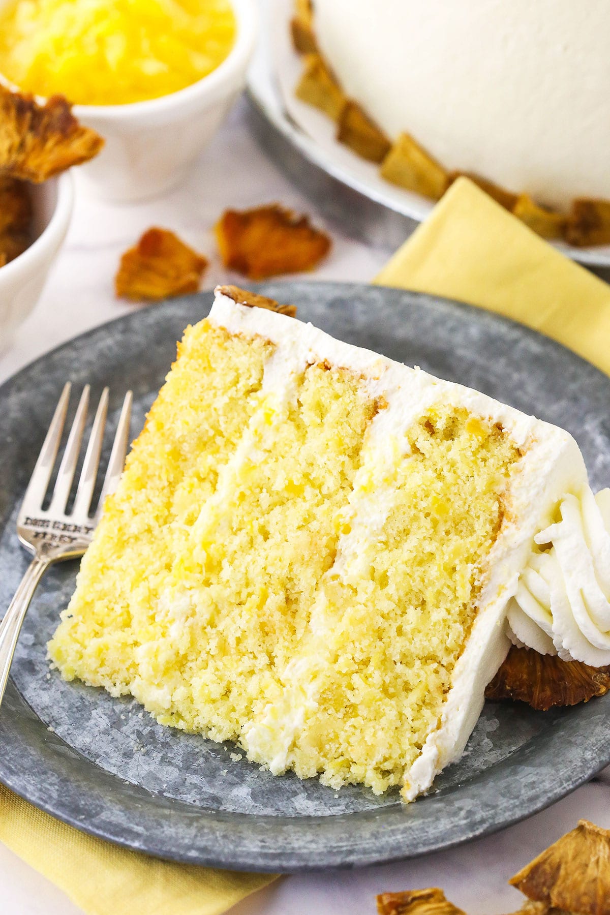 A piece of pineapple cake on a gray plate with a metal fork