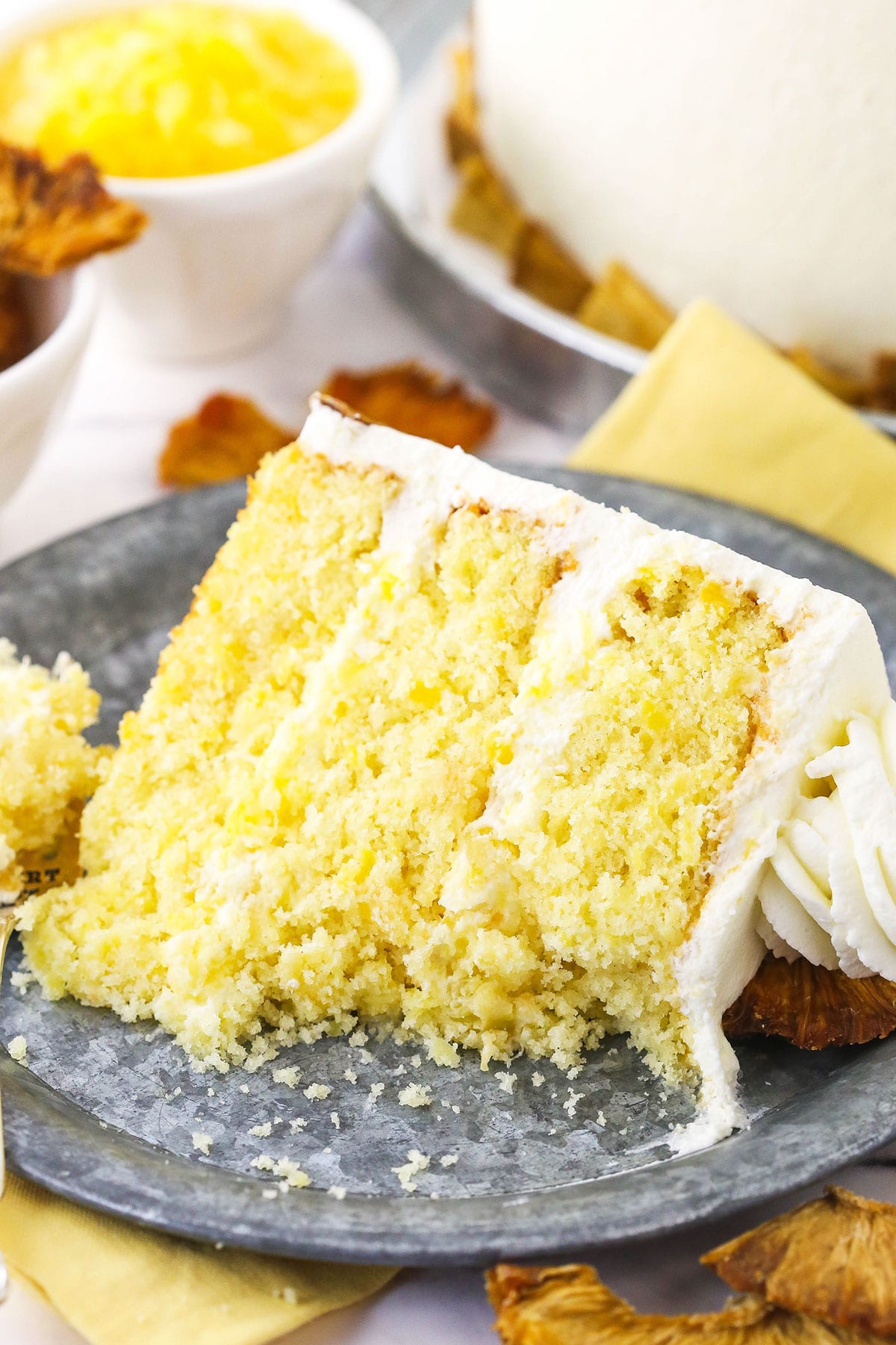 A piece of pineapple layer cake on a plate with two or three bites missing