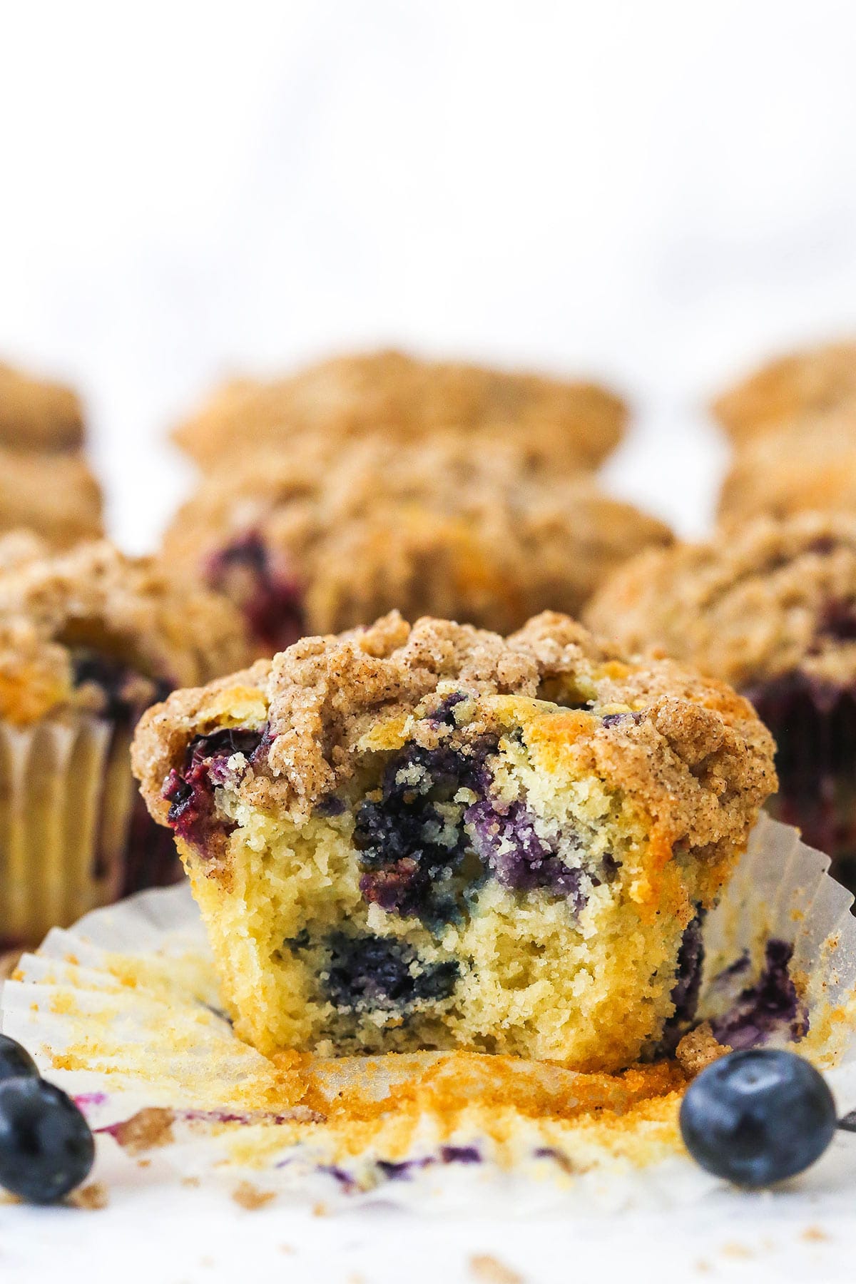 A blueberry muffin on a kitchen countertop with more muffins behind it