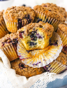 An unwrapped blueberry muffin with a large bite taken out of it