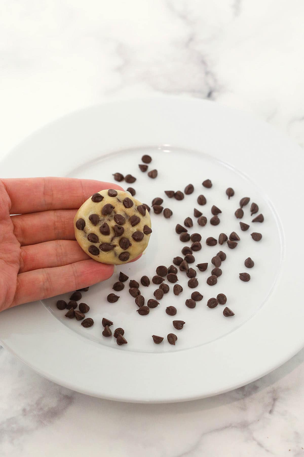 A ball of homemade cookie dough with mini chocolate chips pressed into it