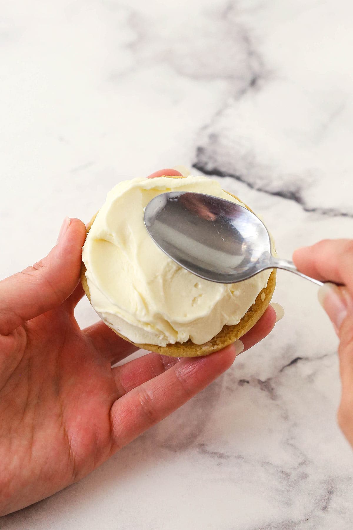 Vanilla ice cream being spread onto a homemade chocolate chip cookie