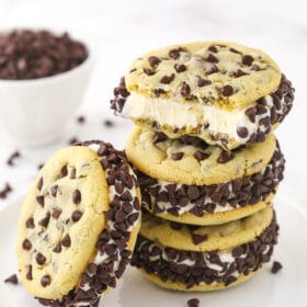 Three ice cream cookie sandwiches stacked on top of one another with a fourth one leaning against the stack