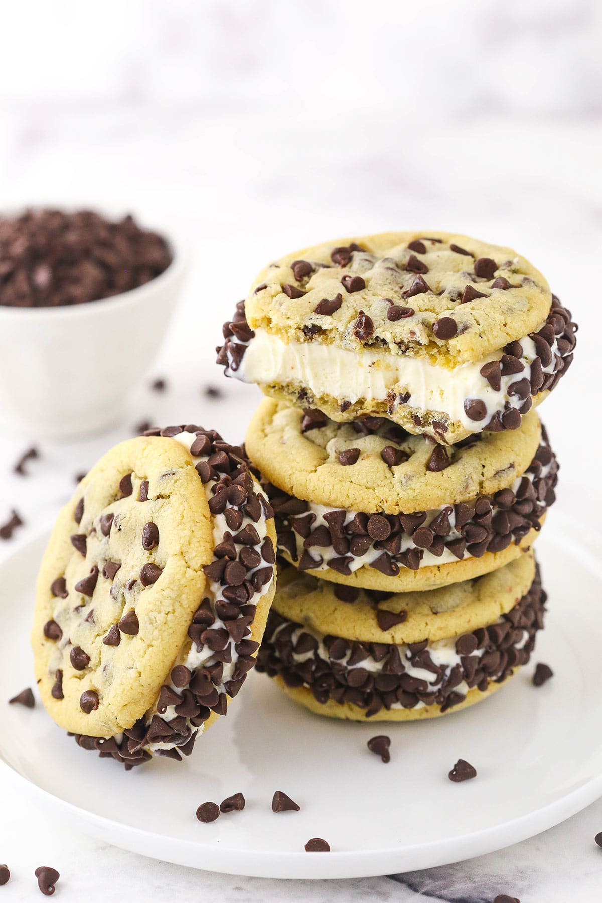 Three ice cream cookie sandwiches stacked on top of one another with a fourth one leaning against the stack